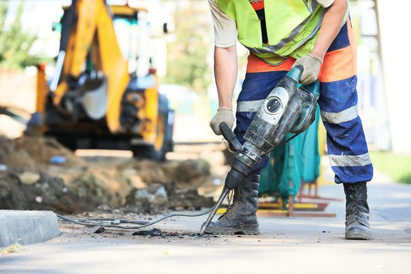 Builder worker with pneumatic hammer drill equipment