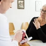 Doctor meeting with woman suffering from rotator cuff injury