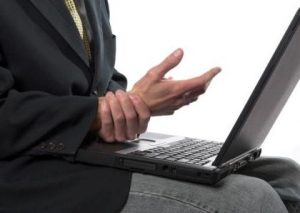 Man rubbing his wrist after typing too long on the laptop