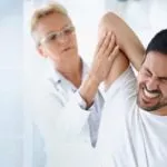 Femail doctor examining man with rotator cuff injury