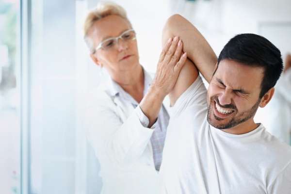 Femail doctor examining man with rotator cuff injury